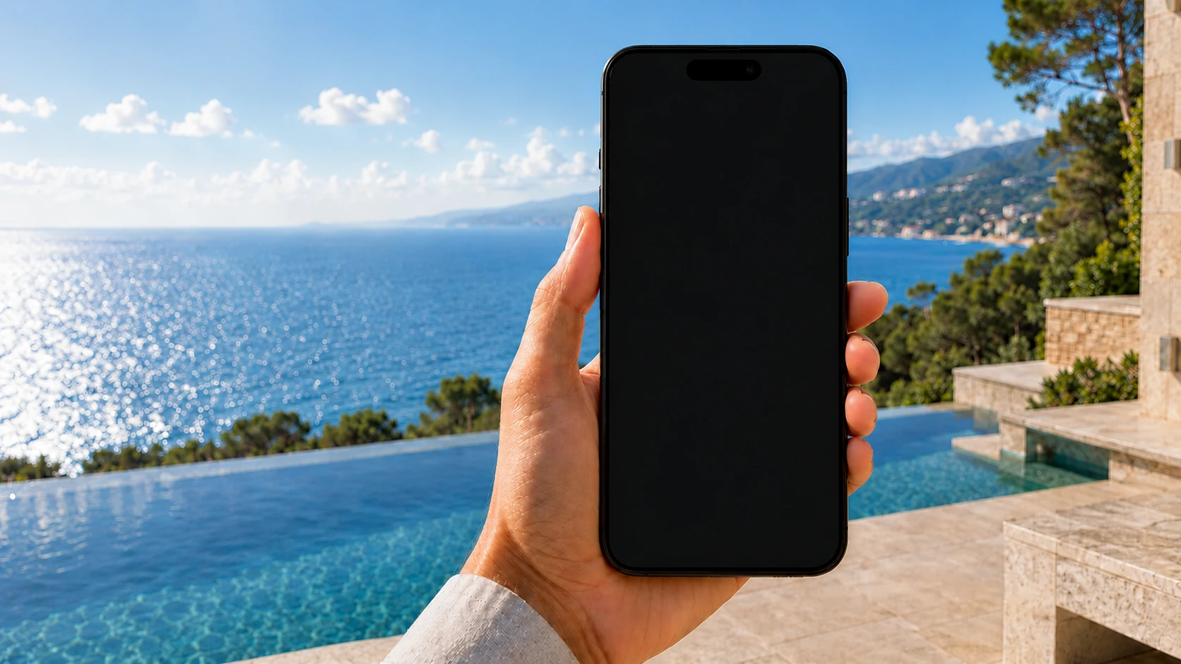 A hand holds a phone showing the PGISR app with a SITE SECURE status and recent reviewed events, on a terrace overlooking the sea.
